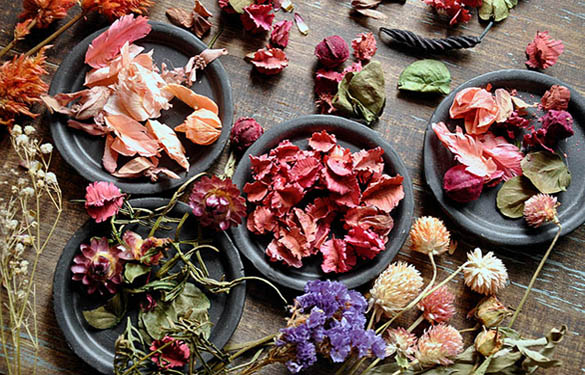 Высушенные розы, лепестки цветов в тарелках на столе